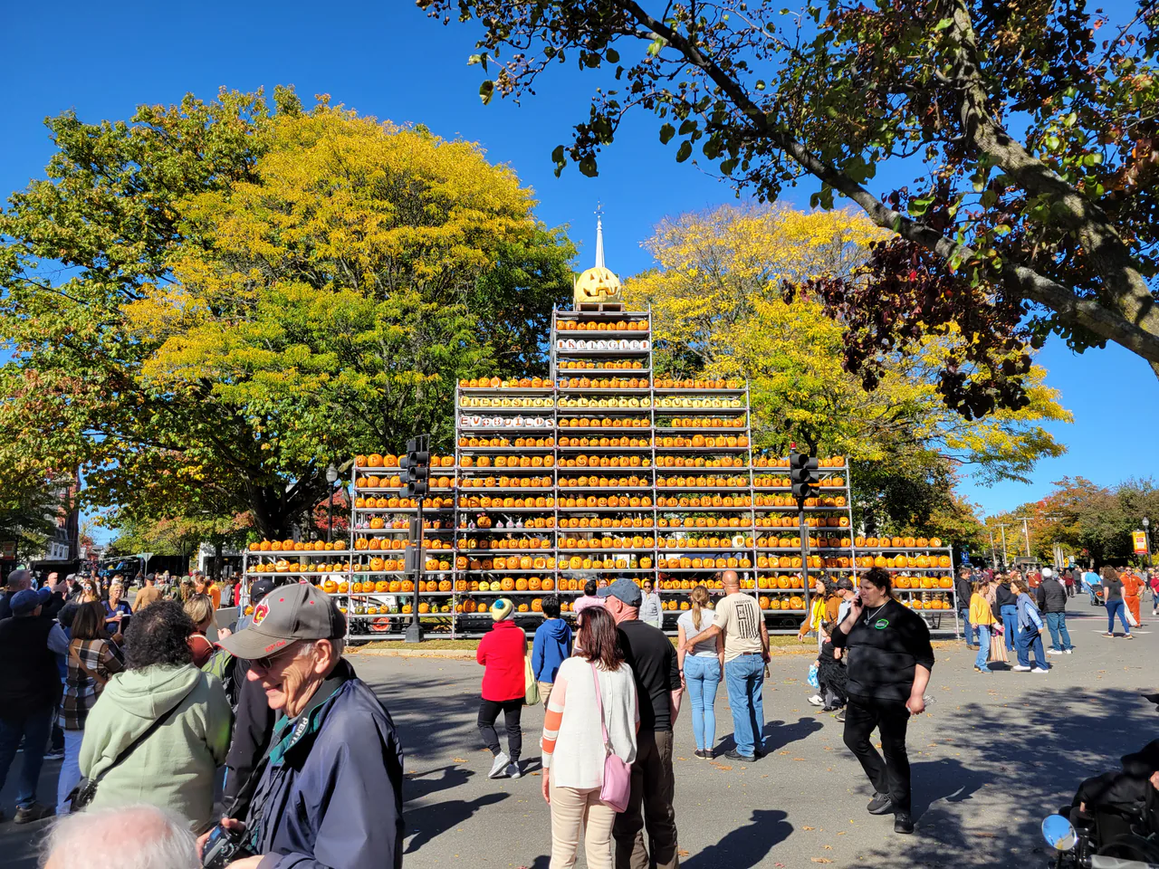 Visitors gathered around a tall jack-o-lantern tower at the Keene Pumpkin Festival in New Hampshire